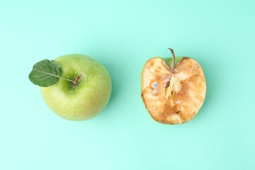 Spoiled apple and good ones on turquoise background, flat lay