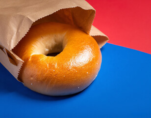 Plain bagels spilling from brown paper bag on colorful surface