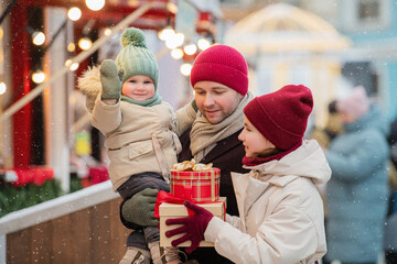father and two children stroll through a city Christmas market