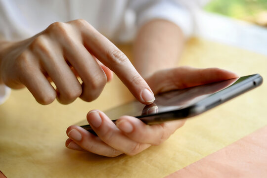 スマホを操作する女性の手元　A close-up of a woman's hands operating a smartphone　Generative AI