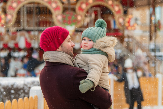 Dad and baby enjoy a snowy day at the Christmas Town Market.