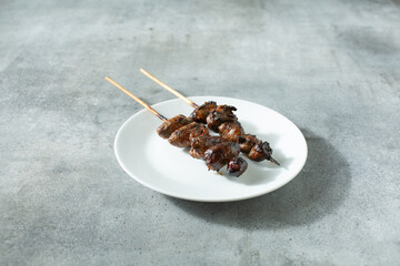 A view of some skewers of BBQ chicken heart, on a plate.