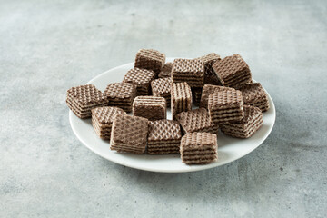 A view of a pile of chocolate wafer cookies, on a plate.