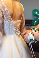 Tying the laces of the bride's wedding dress. Clothes for the bride.