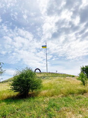 View from below on Unity Hill on Khortytsia island against a background of clouds illuminated by the rays of the midday sun.