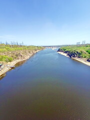 View from the Arch Bridge on the calm water surface of the Dnieper that washes the sandy shores and rocky cliffs of Khortytsia Island.