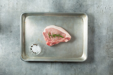 A top down view of a pork chop on a baking sheet.