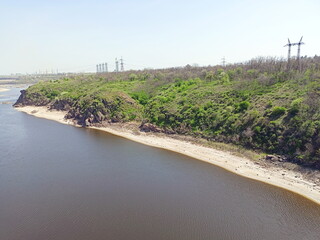 View from the Arch Bridge on the calm water surface of the Dnieper that washes the sandy shores and rocky cliffs of Khortytsia Island.