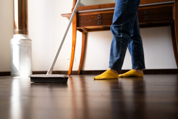 Woman sweeping dust from the wooden floor with a rubber mop in living room at home, female using...