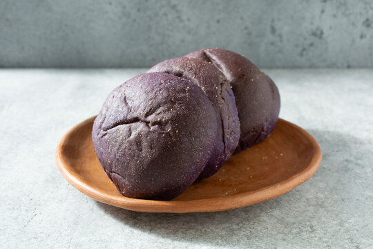 A view of some ube pandesal rolls, on a plate.