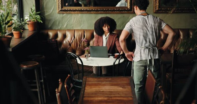 Cafe, waiter and serving with customer on laptop for order, beverage or purchase in restaurant. Woman, barista or man with caffeine or drink for hospitality, accommodation or service in coffee shop