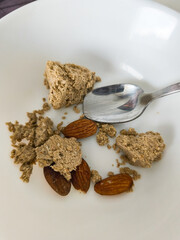 Spoon and almonds with crumbly halva on plate