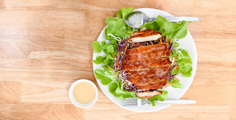 Grilled Chicken Salad: Sliced grilled chicken atop a vibrant salad on wooden table, accompanied by creamy sauce for a healthy and tasty dish.