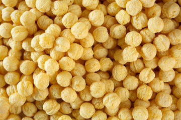 A top down view of a pile of crispy corn puff cereal, as a background.