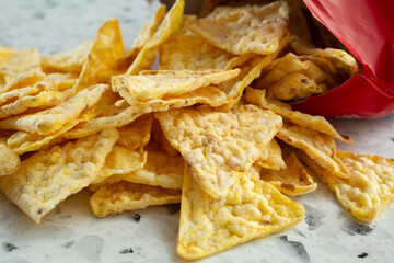 A closeup view of a pile of popped corn chips, spilling out of the package.
