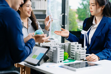 Happy Business Team Holding Earth and Green Ball with Wind Turbines and Building Model for Sustainability