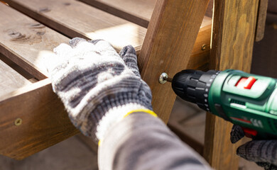 A worker in gloves uses a cordless screwdriver in the household. Cordless drill-screwdriver....