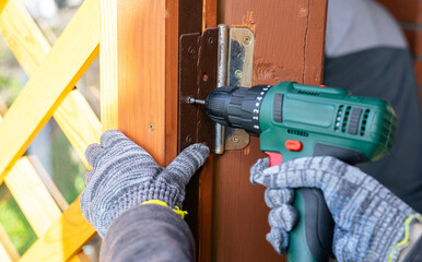 Screwing screws using an electric screwdriver. Assembling furniture using a cordless...