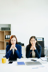Two confident Asian businesswomen in navy suits stand in office. A bold image of leadership, equality, teamwork, and professional empowerment