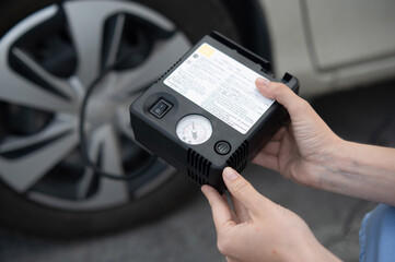 Woman holding a car tire pump. 