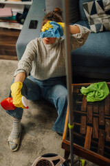 Tired housewife cleaning apartment and wiping sweat from forehead