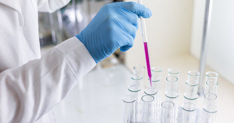 Scientist dripping color liquid into test tube in laboratory. Pipette with a drop and scientific...