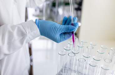 Scientist dripping color liquid into test tube in laboratory. Pipette with a drop and scientific...