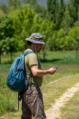 Middle-aged adventurer checking his cell phone on a forest trail