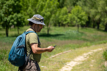Hiker with backpack enjoying her vacation in nature while checking her cell phone