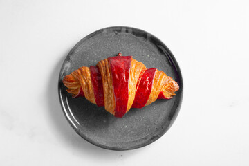 A top down view of a raspberry croissant, on a plate. © DAVID