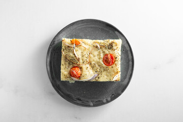 A top down view of a slice of focaccia bread, on a plate.