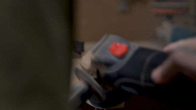 Slow motion close-up of man using electric grinder machinery power tool to shape wooden hardwood blocks for indoor climbing holds on woodwork bench at home garage shed in Australia carpentry project