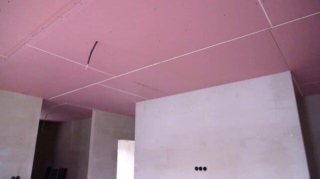Pink fire-proof plasterboard panels installed across entire ceiling area with wires visible