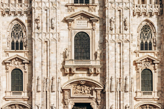Duomo di Milano ornate gothic marble facade with statues and arched windows - Powered by Adobe