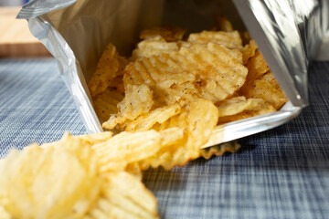 A closeup view of ridged potato chips spilling out of a bag.