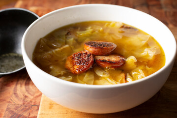 A closeup view of a bowl of kielbasa and cabbage soup.
