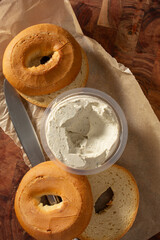 A top down view of a container of dairy-free cream cheese, next to slices of gluten-free bagels.