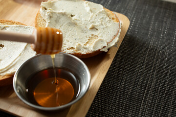 A view of gluten free bagels with diary free cheese spread, featuring a honey dipper.