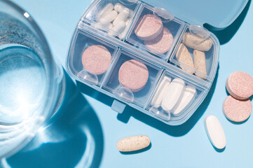 Blue pill organizer, pillbox with vitamins, capsules, tablets, pills, dietary supplements and glass...