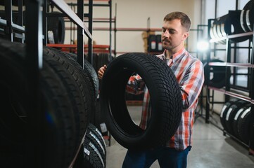 Portrait young man customer examining brand and product characteristics while buying new tires in...