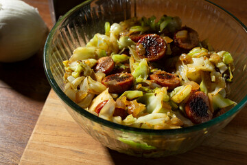 A view of a bowl of kielbasa and cabbage.