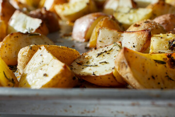 A closeup view of a baking tray of roasted potatoes.