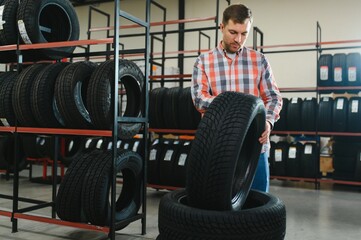 Portrait young man customer examining brand and product characteristics while buying new tires in...