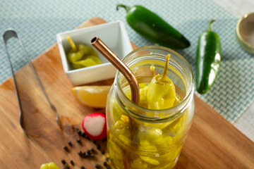 A view of a straw in a jar of pickled pepperoncini peppers.