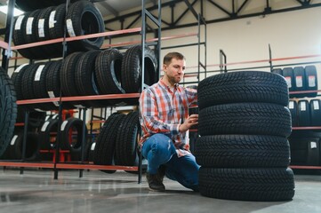 Portrait young man customer examining brand and product characteristics while buying new tires in...