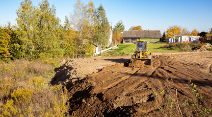 Yellow bulldozer at a construction site. Big wheel excavator leveling and clearing the land plot side view. Moving earthworks soil. Copy space. Building area. Special transport. High quality photo. © Hanna