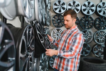 male customer choosing alloy wheel rims at car repair service or auto store