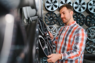 male customer choosing alloy wheel rims at car repair service or auto store