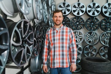 male customer choosing alloy wheel rims at car repair service or auto store