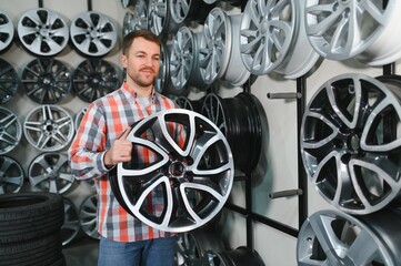 male customer choosing alloy wheel rims at car repair service or auto store